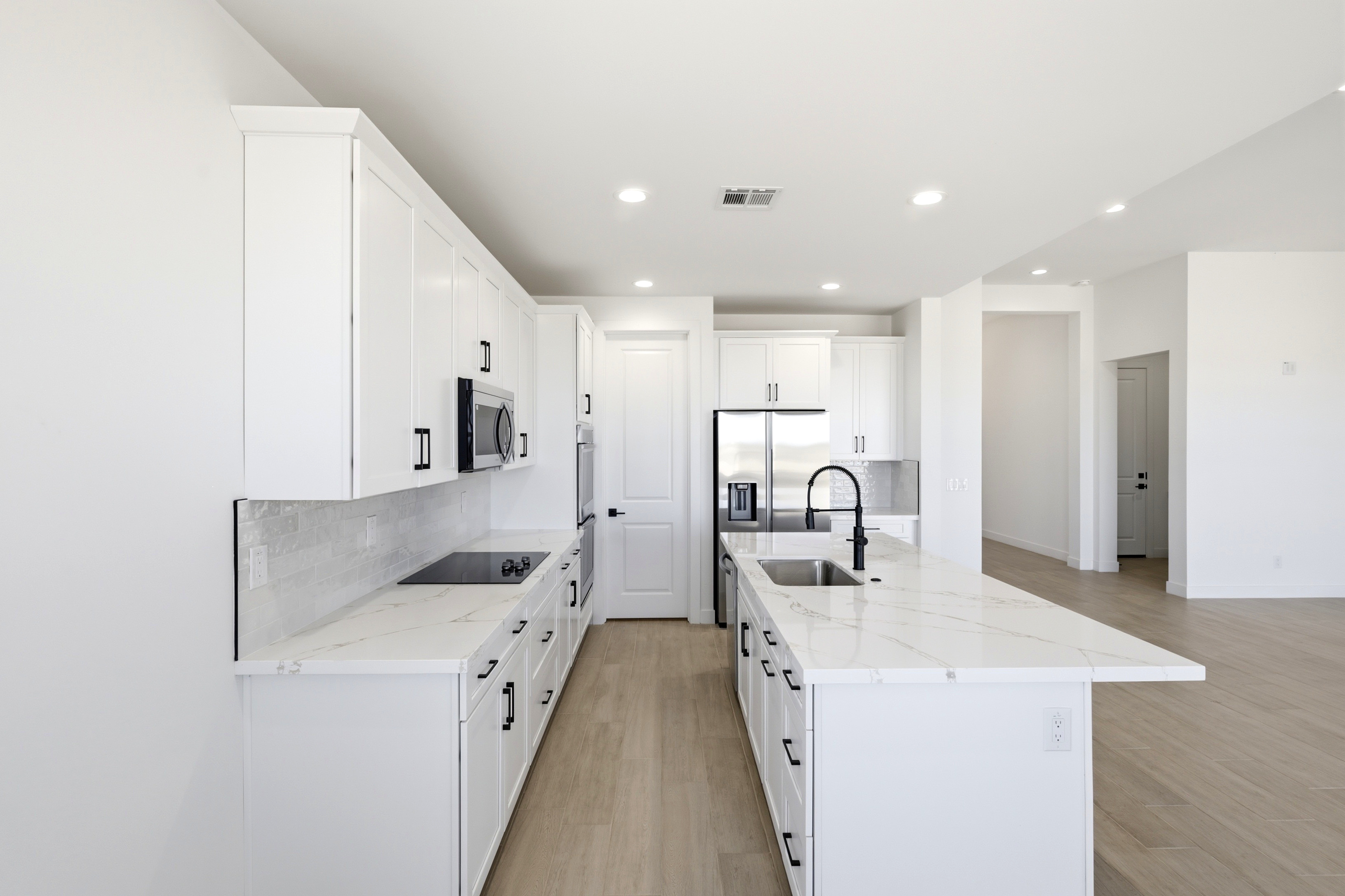 Bright white kitchen with quartz island in a completed Jematell home