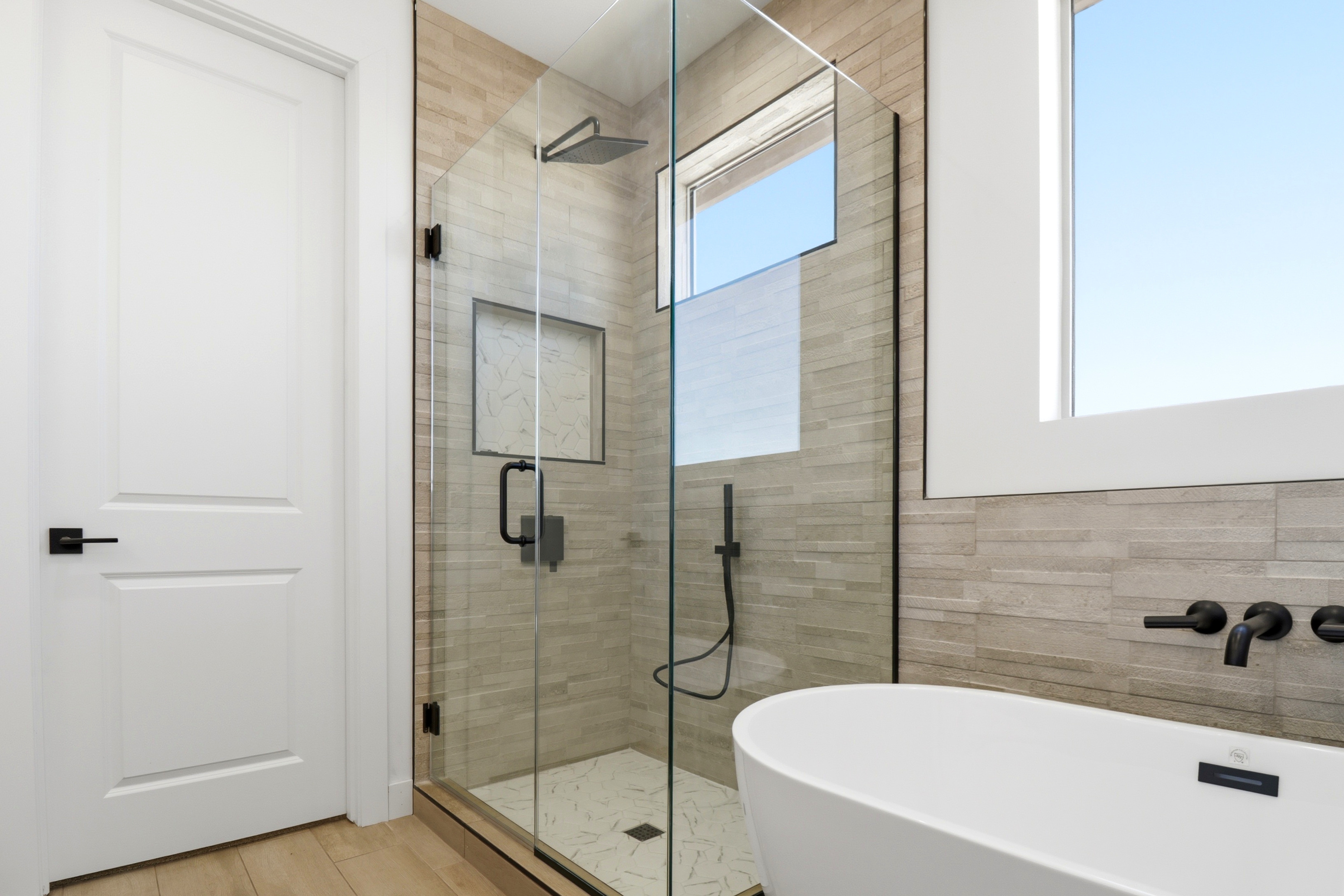 Spa-style primary bathroom with walk-in shower and freestanding tub in a completed Jematell home