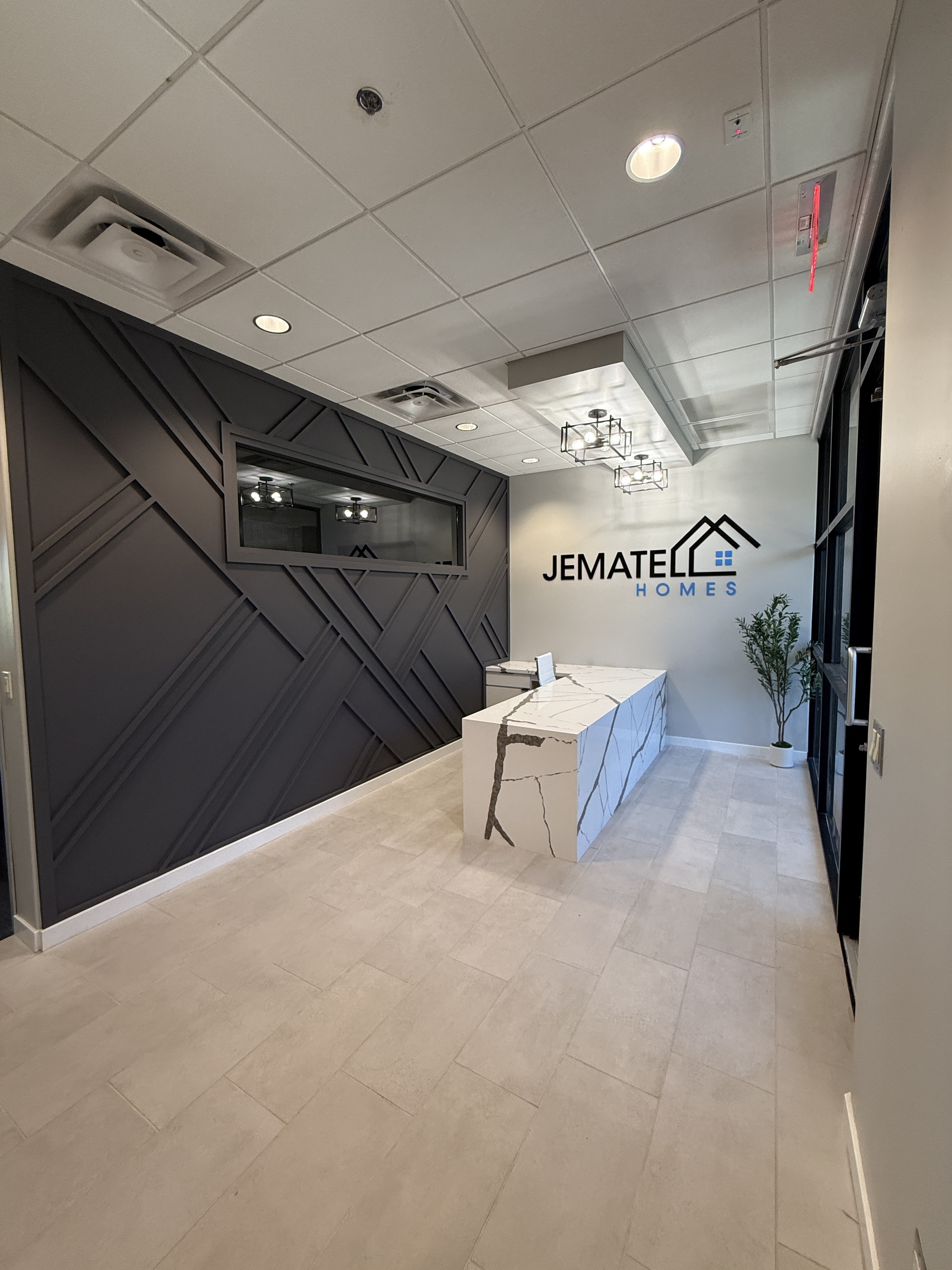 The Jematell Homes office reception in Scottsdale, Arizona, with the company logo on the wall and a natural stone reception desk